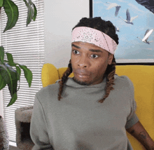 a man with dreadlocks wearing a headband with a flower on it