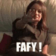 a woman is sitting on a couch making a stop sign with her hand and the words fafy !