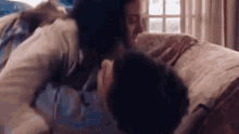 a man and a woman are kissing on a bed in a room .