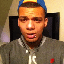 a young man wearing a baseball cap and a jacket with the letter s on the chest
