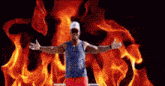 a man with his arms outstretched is standing in front of flames