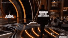 a man walking on a stage with the words chocobhoss giving me golden ticket on the screen