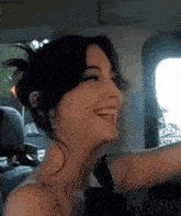 a woman in a car is smiling and looking at the camera