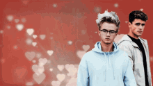 two young men standing next to each other in front of a red background with hearts