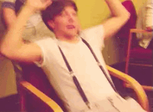 a man is sitting in a chair with his arms in the air