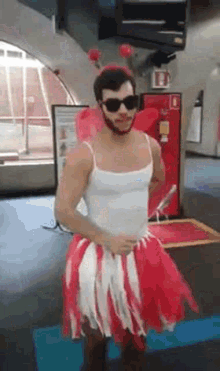 a man with a beard is wearing a red and white skirt and sunglasses .
