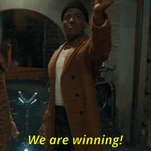a man in a plaid coat says we are winning in yellow letters