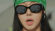 a woman wearing sunglasses and a green bandana on her head