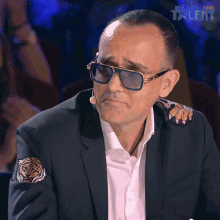 a man wearing sunglasses and a suit has the word talent on the bottom right