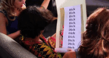 a woman is holding a piece of paper that says dick