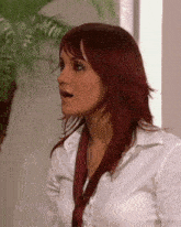 a woman with red hair wears a white shirt and red tie