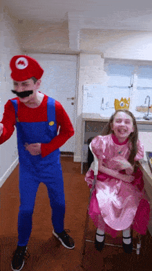 a boy dressed as mario and a girl dressed as princess peach laugh together