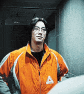 a man wearing glasses and an orange jacket that says palace on it