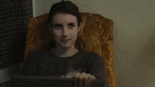 a woman is sitting in a chair holding a box of cereal in her hands .