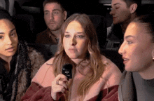 a group of people are sitting in a car and one woman is holding a rode remote control