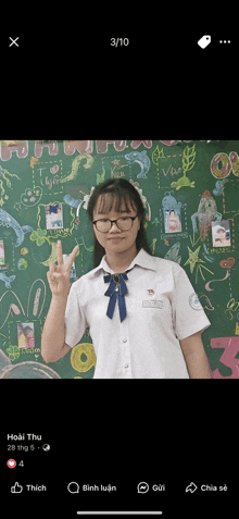 a girl giving a peace sign in front of a green board