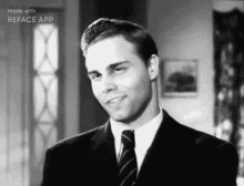 the man is wearing a suit and tie and smiling in a black and white photo .