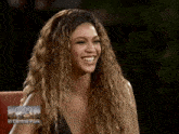 a woman with curly hair is laughing in front of a screen that says ellen in central park