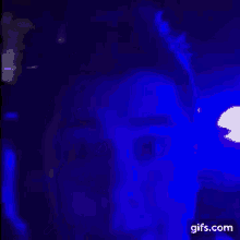 a close up of a person 's face with a blue light behind it .