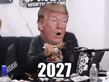 a man with a donald trump head in front of a microphone with the year 2027