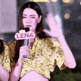 a woman holding a microphone with lena on it