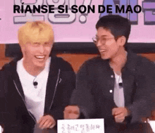 a couple of men are sitting next to each other and laughing together .