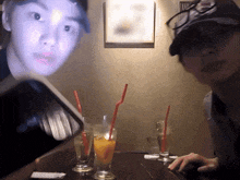 two people sitting at a table with drinks and straws