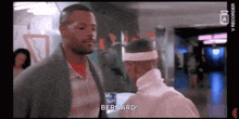 a man wearing a white headband is talking to another man in a movie .