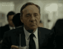 a man in a suit and tie is sitting at a table with a cup of coffee .
