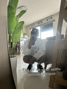 a man taking a selfie in front of a mirror with the words tag us on your selfie @studioatique