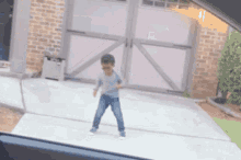 a young boy is dancing in front of a brick garage