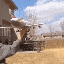 a person is holding a model airplane in their hand in front of a house .