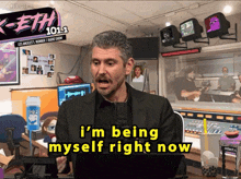 a man says i 'm being myself right now in front of a sign that says keith 101.1