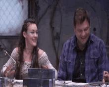 a man and a woman are sitting at a table laughing together