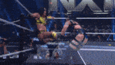 two women are wrestling in a ring with a w logo on the wall behind them