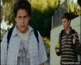 two boys are standing next to each other on a sidewalk .