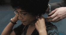 a woman wearing glasses and earrings is being touched by a man