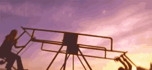 a woman sits on a seesaw at sunset while another woman swings on it