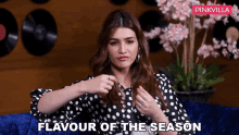 a woman in a black and white polka dot shirt is sitting on a blue couch with the words flavour of the season above her