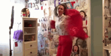 a woman in a red dress is standing in front of a wall with drawings on it .
