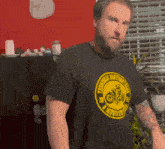 a man with a beard wears a black shirt with a yellow motorcycle logo on it