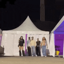 a group of people are standing next to each other in front of a tent .