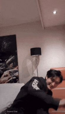 a man in a black shirt with the word space on it is sitting on a bed