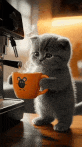 a kitten is holding a cup of coffee with a mouse on it .