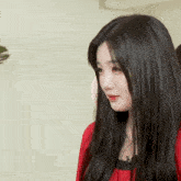 a woman with long black hair is wearing a red sweater