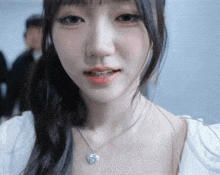 a close up of a woman wearing a necklace with a heart on it