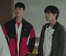 two young men standing next to each other one of whom is wearing a jacket that says asics