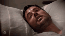 a man is laying in a hospital bed with a nbc logo on the bottom