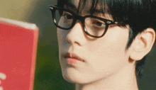 a close up of a person wearing glasses looking at a book