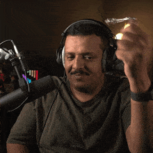 a man wearing headphones and a kappa t-shirt is sitting in front of a microphone